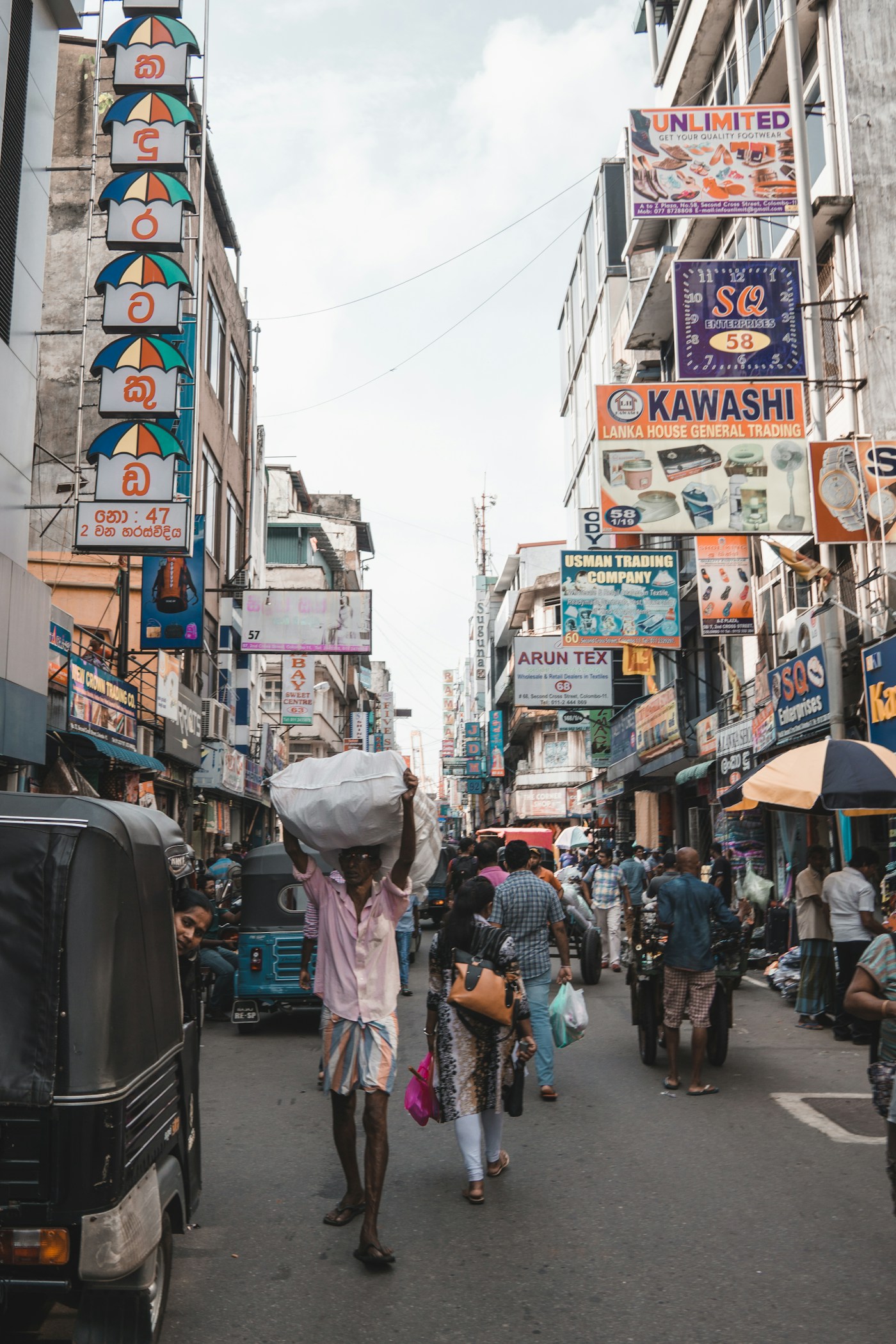 People going about their day on a busy market street in Colombo, Sri Lanka.